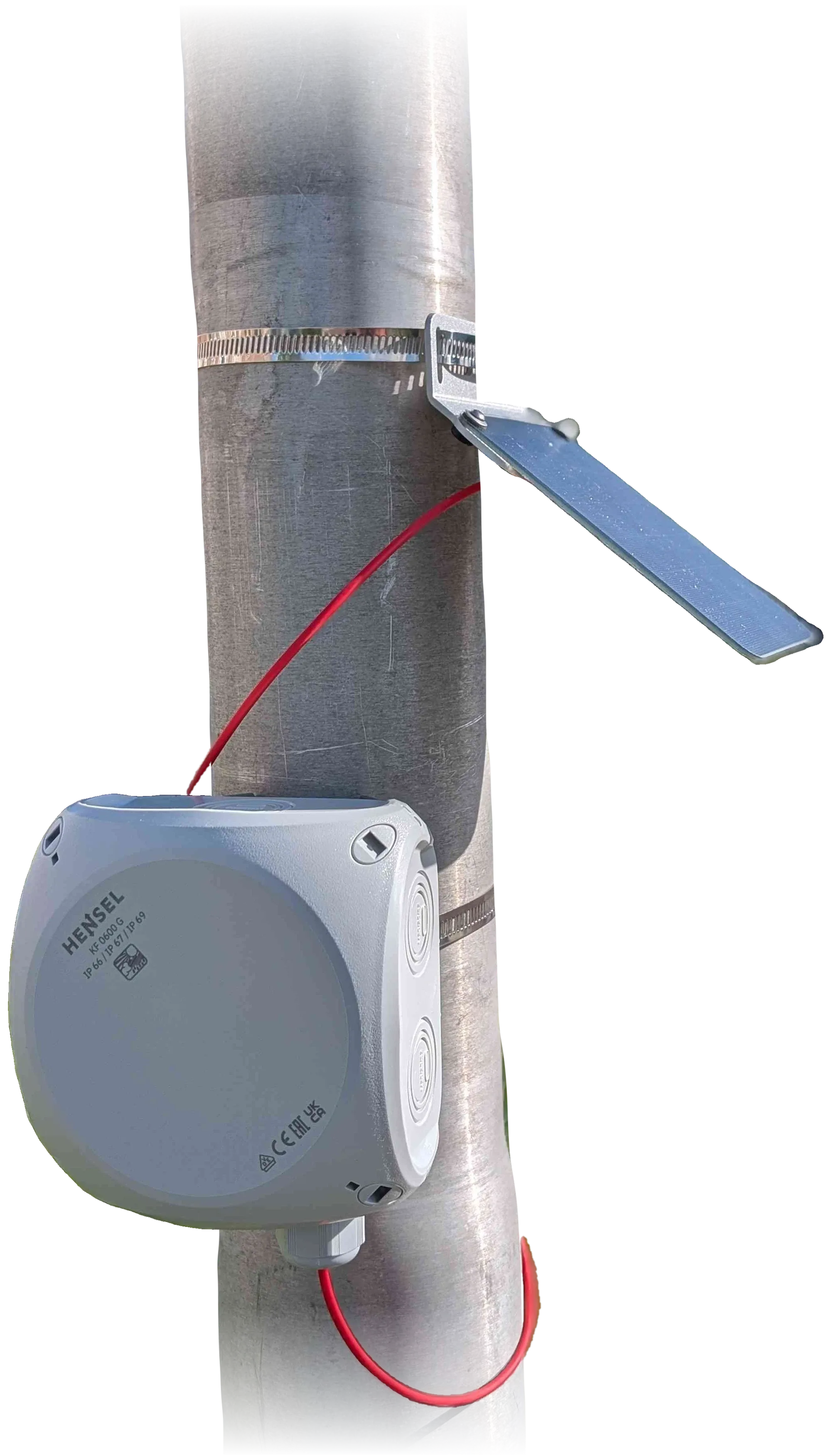 The unit on a pole: solar panel on its bracket, grey enclosure, red solar cable